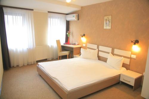 a bedroom with a white bed and a desk at Pension Cleopatra in Târgu-Mureş