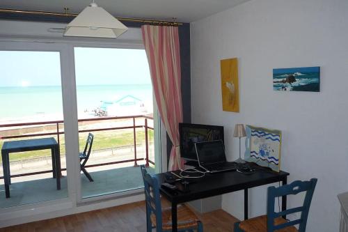 Cette chambre dispose d'un balcon et d'un bureau avec un ordinateur portable. dans l'établissement Appartement face à la mer, à Criel-sur-Mer