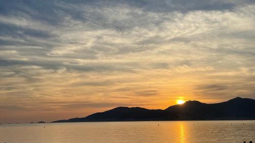 un coucher de soleil sur l'eau avec une montagne en arrière-plan dans l'établissement Appartement Ajaccio F3 6 couchages, à Ajaccio