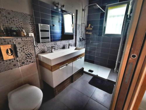 une salle de bain avec un lavabo et une douche avec du carrelage bleu dans l'établissement La Bastide Provençale, à Pourrières