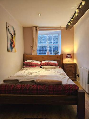a bedroom with a large bed with a window at Private Woody Apartment, 2 King Beds, Very Centre Stamford in Lincolnshire