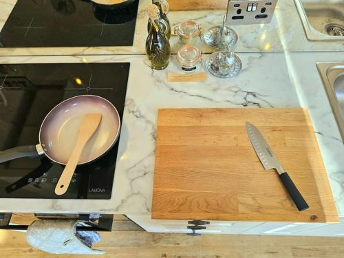 a cutting board with a pan and a knife on a counter at Private Woody Apartment, 2 King Beds, Very Centre Stamford in Lincolnshire