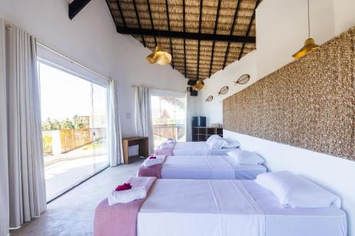 a bedroom with four beds and a large window at Casa de Sal Ocean - Cajueiro da Praia (Vista Mar) in Cajueiro