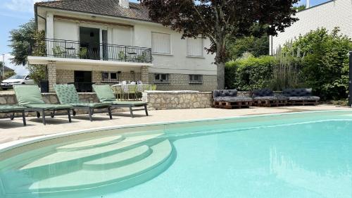 une piscine avec des chaises et une maison dans l'établissement Villa d'Eden - Piscine chauffée, à Cloyes-sur-le-Loir