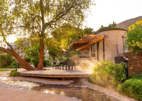 a patio with a table and chairs next to a pond at Avalon Springs by Dream Resorts in Montagu