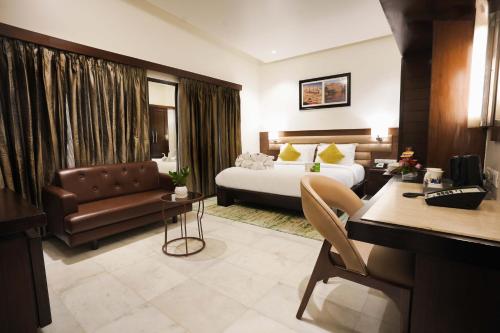 a hotel room with a bed and a couch at Leisure Inn Grand Chanakya in Jaipur