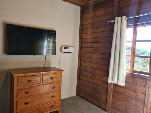 ein Schlafzimmer mit einer Kommode und einem Flachbild-TV in der Unterkunft Chalé na serra da mantiqueira in Piranguçu