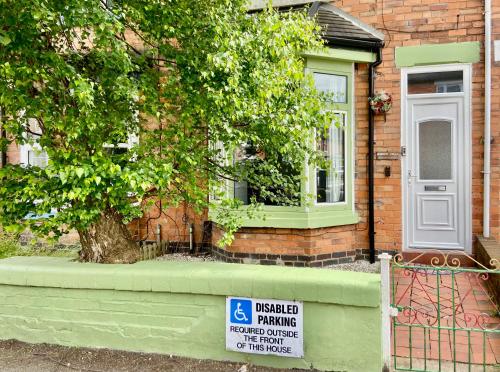 a house with a sign in front of it with a tree at Garden Villa in Stafford