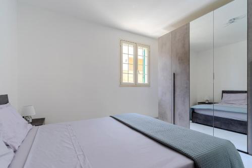 Un dormitorio blanco con una cama y una ventana. en Casa Chiaraluna by BarbarHouse, en Porto Cesareo