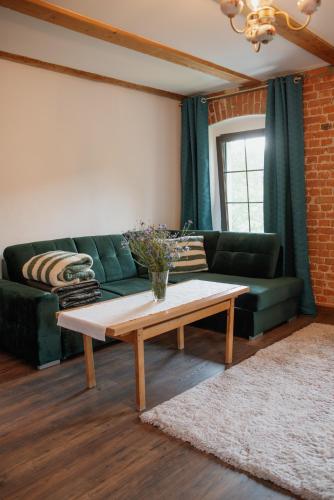 a living room with a green couch and a coffee table at Apartament Zielono Mi, Pilchowice in Wleń