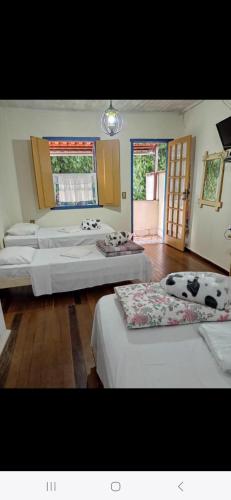 a large bedroom with three beds and a window at Pousada Caminho do Trem in Tiradentes