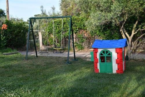 a toy dog house in the grass next to a swing at Endless View loft in Mesimvría