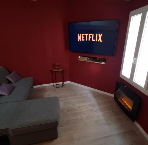 un salon avec un canapé et une télévision au mur dans l'établissement Appartement Romantique Climatisé BELORIZON - 30 min de la mer, à Pignans