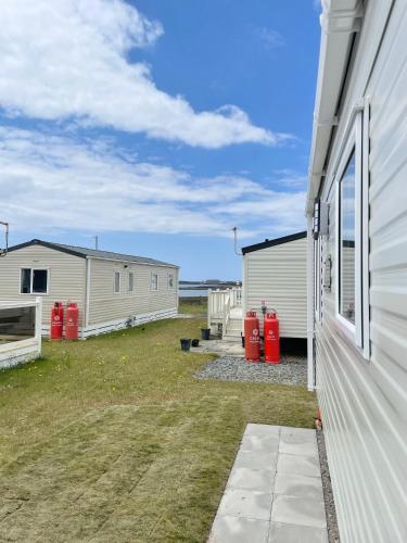 a group of mobile homes next to a building at Trecco Bay Caravan Cosy Coastal Retreat in Porthcawl