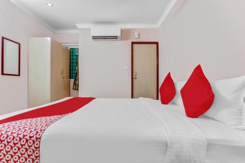 ein Schlafzimmer mit einem großen weißen Bett mit roten Kissen in der Unterkunft PN SAMY INN in Puducherry
