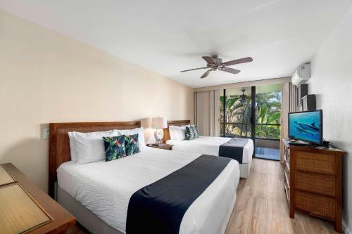 a bedroom with two beds and a flat screen tv at Kona Pacific D524 Kauhale in Kailua-Kona