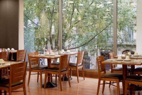 a restaurant with wooden tables and chairs and a large window at Best Western Premier Hotel Dante in Barcelona