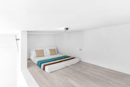 a white bedroom with a bed with a rainbow blanket at Sabhé Gallipoli in Gallipoli