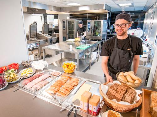 Ein Mann steht in einer Küche mit einem Tisch. in der Unterkunft Lofoten sommerhotell og vandrerhjem in Kabelvåg