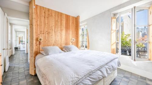 une chambre avec un grand lit blanc et des fenêtres dans l'établissement Famous parisian designer's pied-à-terre in Le Marais, à Paris