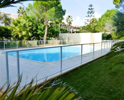 une piscine avec une clôture à côté d'une cour dans l'établissement Le Palm, appartement climatisé pour 4 personnes avec vue mer et piscine sur le Port d'Hyères, à Hyères