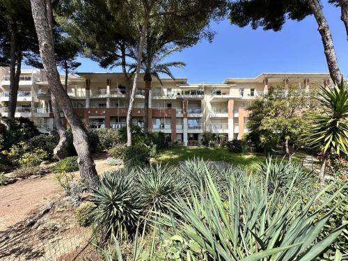un grand immeuble avec des palmiers et des plantes dans l'établissement Le Palm, appartement climatisé pour 4 personnes avec vue mer et piscine sur le Port d'Hyères, à Hyères