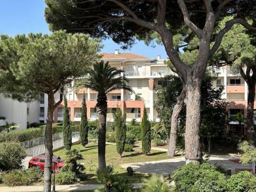 - une vue sur un bâtiment avec des arbres devant lui dans l'établissement Le Palm, appartement climatisé pour 4 personnes avec vue mer et piscine sur le Port d'Hyères, à Hyères