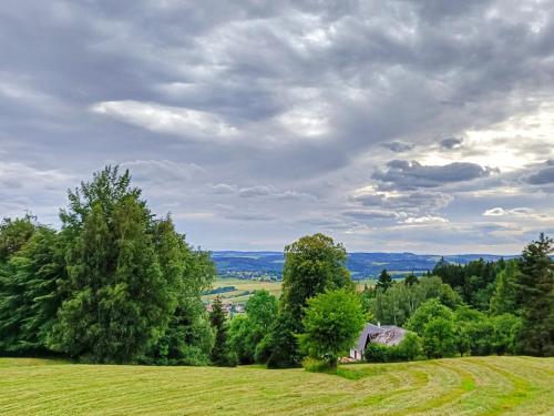 a green field with trees and a house on a hill at Chaloupka pod lípou in Malé Svatoňovice