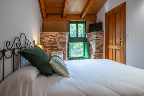 a bedroom with a large white bed with green pillows at Alojamientos rurales O Acivro in A Rúa