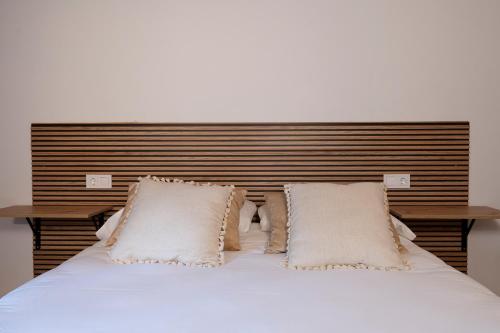a bed with white pillows and a wooden headboard at Alojamientos rurales O Acivro in A Rúa