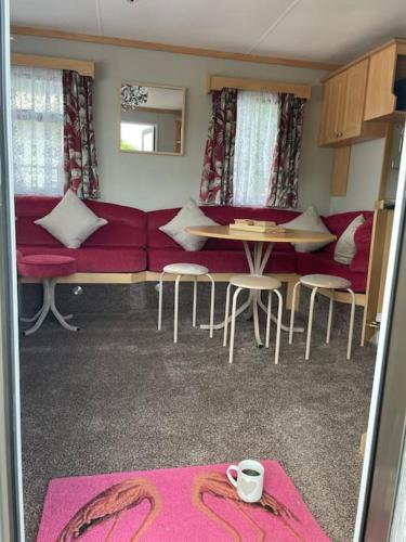 a living room with a red couch and a table and chairs at Three bed static caravan with fantastic views and hottub in Swansea