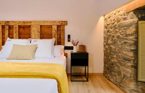 a bedroom with a bed and a stone wall at Hotel Molí Cardedeu in Cardedeu