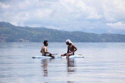two people sitting on rafts in the water at Marroan Acc in Tuk Tuk