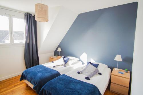 une chambre avec deux lits et un mur bleu dans l'établissement -FRESNEL- MAISON DE BORD DE MER - GRANDE TERRASSE, à Concarneau