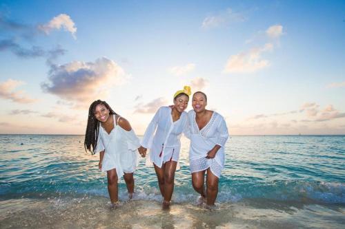 three women in white walking in the water on the beach at Divi Village Condo 6 J.E. Irausquin Blvd 93 in Palm-Eagle Beach