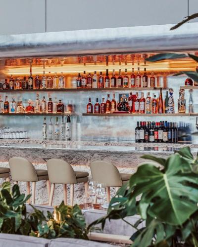 a bar with chairs in front of a counter with alcohol bottles at Lux Aka Brickell Condo in Miami