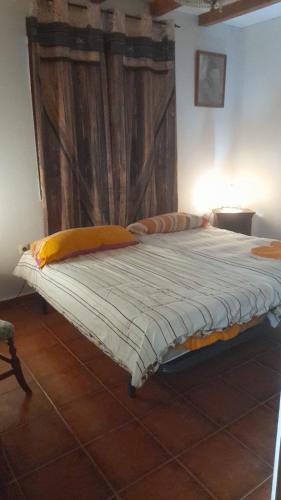 a large bed in a room with a wooden wall at Habitacion en Casa Huelves in Huelves
