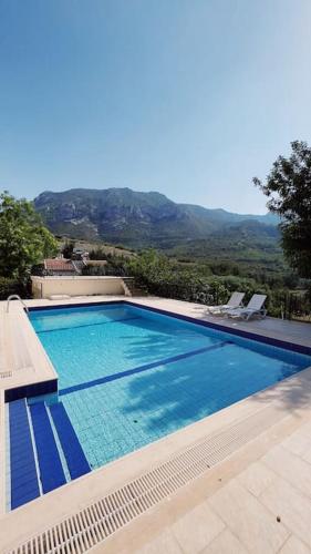 a swimming pool with a view of a mountain at Tropical Mountain Villa With Pool & Sea View in Kérynia