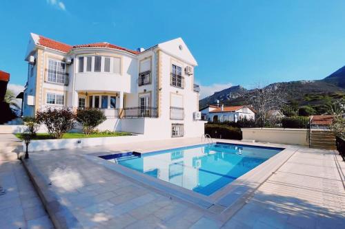 a large house with a swimming pool in front of it at Tropical Mountain Villa With Pool & Sea View in Kérynia
