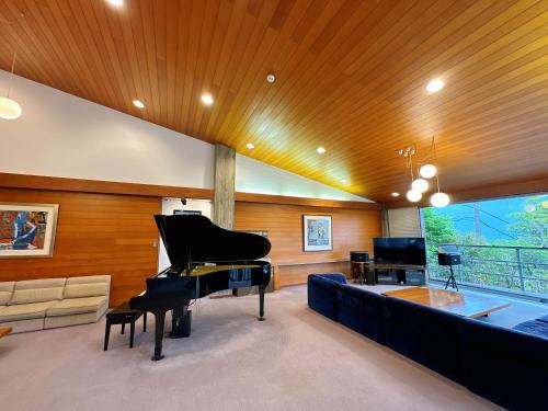 a living room with a piano and a couch at 貸温泉リゾートBLOOM in Ito