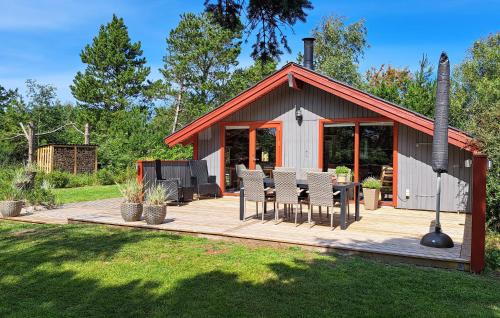 a small cabin with a wooden deck with chairs at Holiday Home Blåvand With Fireplace Vi in Blåvand