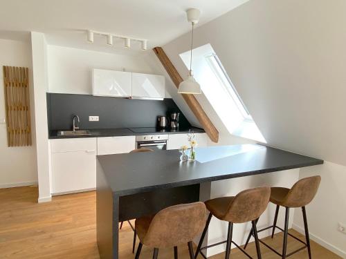a kitchen with a black counter and some chairs at Timmenhus - neue Ferienwohnungen im historischen Bauernhaus in Timmendorfer Strand