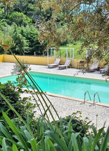 a swimming pool with two lounge chairs next to it at Casas do Alpendre in Óbidos