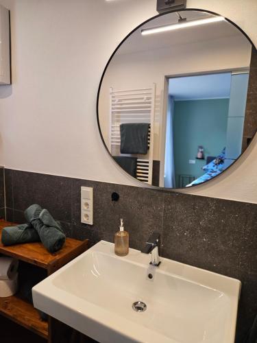 ein Badezimmer mit einem weißen Waschbecken und einem Spiegel in der Unterkunft Schorn³ Appartements in Zell an der Mosel