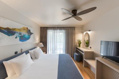 a hotel room with a bed and a ceiling fan at Blazer Suites Hotel in Athens