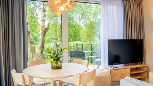 a living room with a table and a large window at Apartament w willi z ogrodem SurfingBird Dźwirzyno in Dźwirzyno