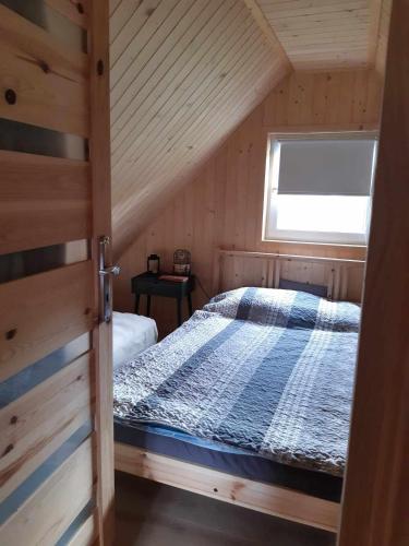 a bedroom with a bed in a wooden cabin at Chatka nad Stawami in Bierdzież