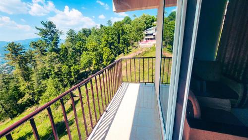a balcony of a house with a view of trees at Aqua Apartment Murree in Murree