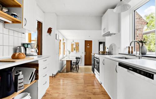 a kitchen with white cabinets and a wooden floor at 4 Bedroom Gorgeous Home In Aakirkeby in Vester Sømarken