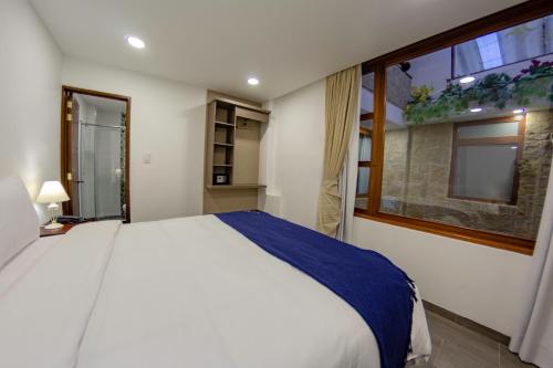 a bedroom with a large white bed and a window at Hotel Boutique San Marcos Chiquinquirá in Chiquinquirá